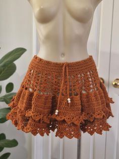 an orange crocheted skirt is displayed on a mannequin