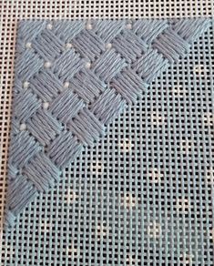 a close up of a knitted piece of cloth on a woven tablecloth with holes in the middle