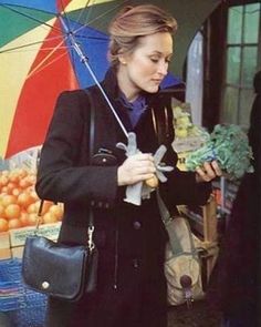 a woman is holding an umbrella and looking at vegetables