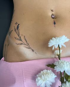 a close up of a woman's stomach with flowers on the side and behind her