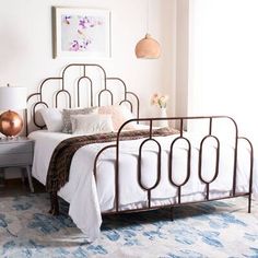 a bedroom with a metal bed frame and blue rugs on the floor next to a window