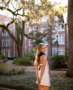 a woman standing in front of a tree with her back to the camera