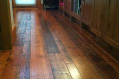 a wood floor in a kitchen with wooden cabinets and drawers on either side of the counter