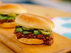 two sandwiches sitting on top of a wooden cutting board