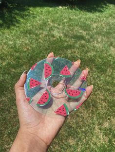 a hand holding a glass plate with watermelon slices on it in the grass