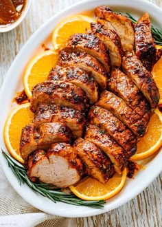 sliced pork and oranges on a white plate