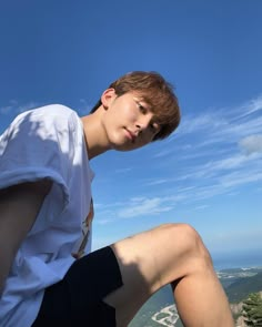 a young man sitting on top of a cliff