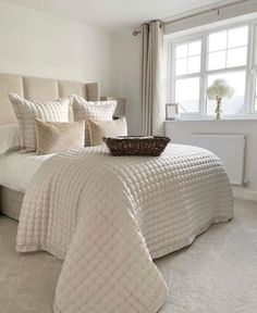 a bedroom with white walls and carpeted flooring has a basket on the bed