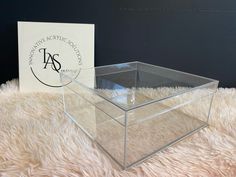 a clear box sitting on top of a fluffy white carpet next to a sign that says international acrylic council