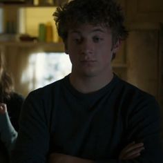 two people standing in a kitchen with one holding his arms crossed and looking at the camera