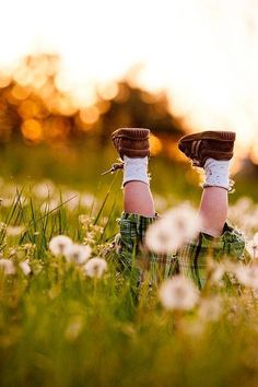 the person is laying down in the grass with their feet up and wearing mitts