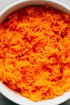 a white bowl filled with shredded carrots on top of a table