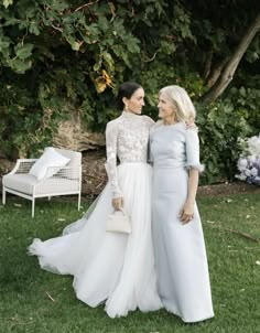 two women standing next to each other in the grass