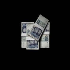 several stacks of money sitting on top of each other in front of a black background