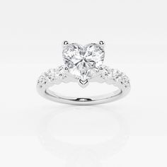 a heart shaped diamond ring with diamonds on the band and side stones set in 18k white gold