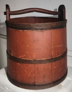 an old wooden barrel sitting on top of a white toilet seat next to a wall