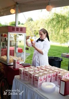 a woman standing in front of a table filled with cakes and candy boxes on top of it