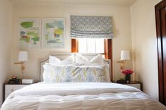 a bed with white comforter and pillows in a bedroom next to two pictures on the wall