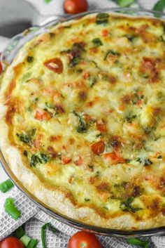 a pizza sitting on top of a pan covered in cheese and toppings next to tomatoes