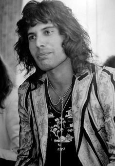 a black and white photo of a young man with long hair wearing a leather jacket