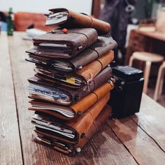 a stack of notebooks sitting on top of a wooden table next to a camera