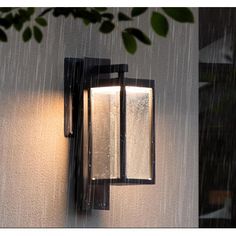 an outdoor wall light with rain coming down on it