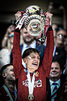 a man holding up a trophy in front of his face with other people behind him