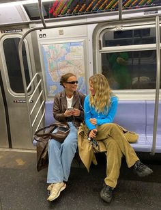 two people sitting on a subway train next to each other