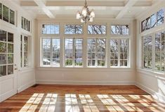 an empty room with large windows and wooden floors