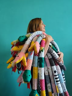 a woman is holding a large pile of stuffed animals in front of a blue wall