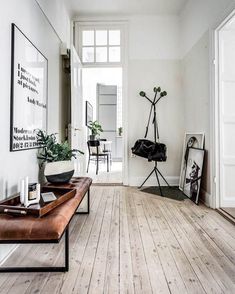 a white room with wooden floors and pictures on the wall, along with a bench