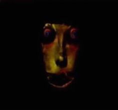 a creepy looking face in the dark with red and yellow lights on it's eyes