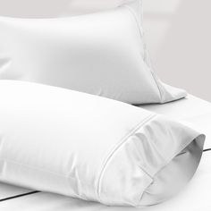 two white pillows sitting next to each other on a bed