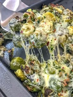 a spatula scooping cheese from a casserole dish with broccoli and peppers