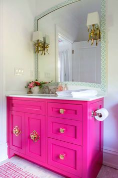 a bright pink vanity with gold handles and knobs on the drawers is featured in this bathroom