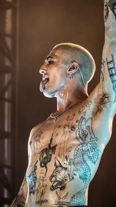 a shirtless man with tattoos on his chest and arms raised up in the air