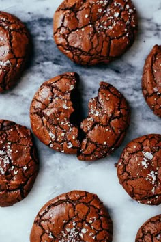 chocolate cookies with powdered sugar are on a marble countertop and have been cut in half