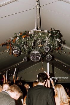 a group of people standing under a tent with lights hanging from it's ceiling