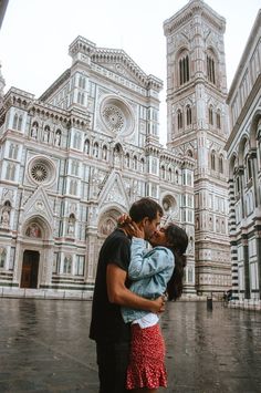 a man and woman embracing in front of a cathedral