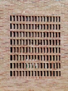 a red brick wall with a hole in the middle that is filled with small white candles