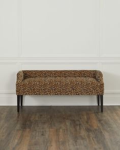 a leopard print bench sitting on top of a hard wood floor next to a white wall