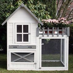 a white chicken coop with flowers growing on top