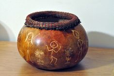 a wooden bowl sitting on top of a table next to a wall with drawings on it