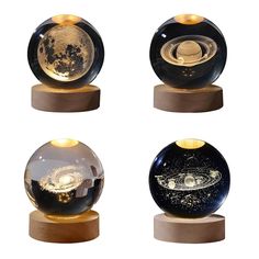 three glass globes on wooden bases with gold and black designs, each containing an image of the solar system