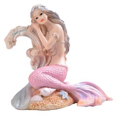 a little mermaid figurine sitting on top of a rock next to a starfish