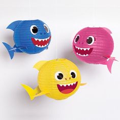 three paper fish hanging from strings in the shape of small balls with eyes and teeth on them