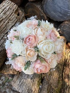 a bridal bouquet sitting on top of a piece of wood next to some logs