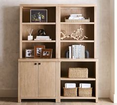 a wooden bookcase with baskets and pictures on it