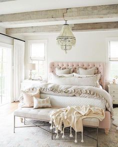 a bedroom with a bed, chandelier and pillows