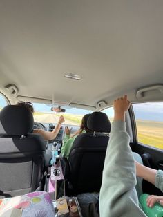 two people sitting in the back seat of a car with their hands up to the ceiling